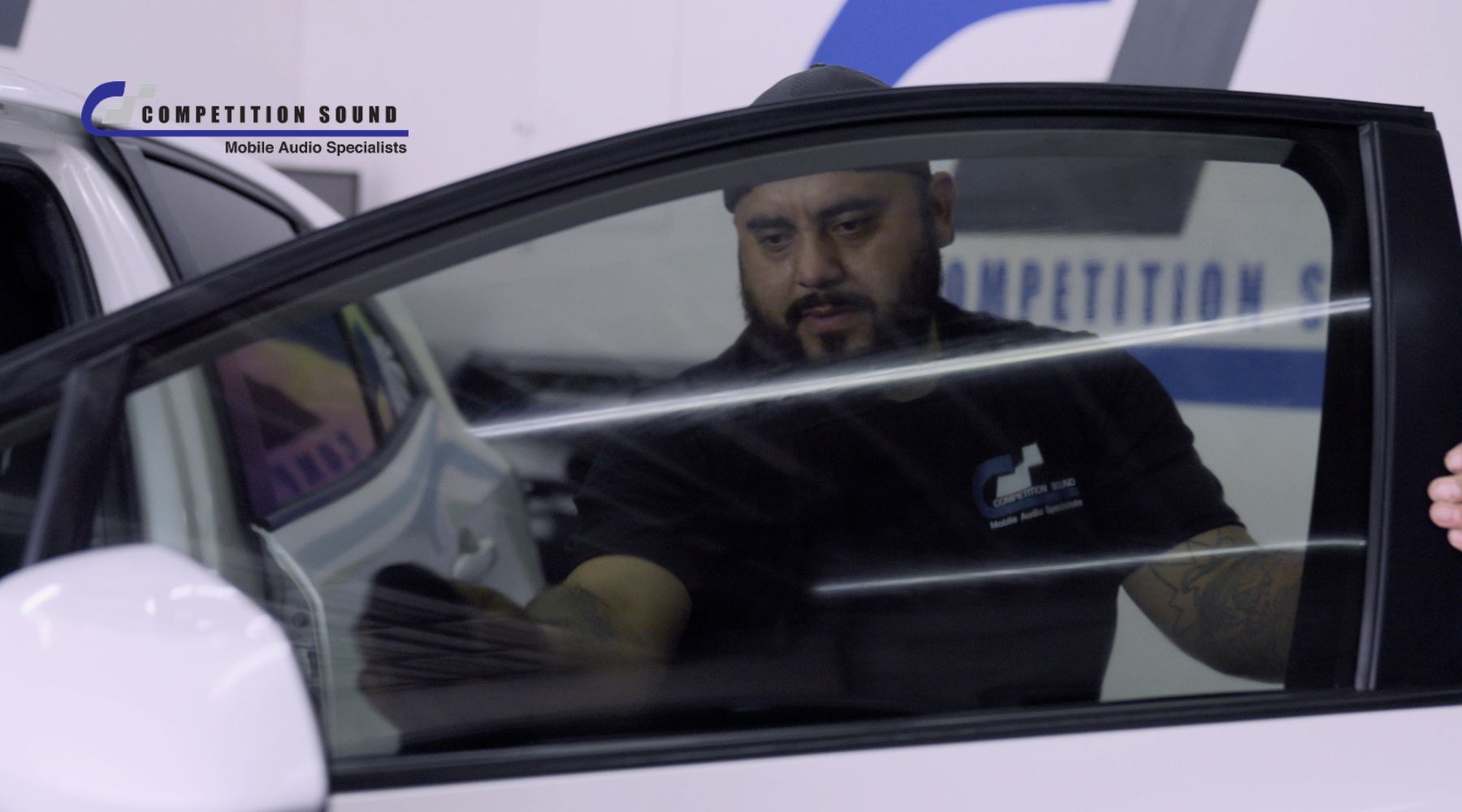 Competition Sound technician installing ceramic window tint on a vehicle window for a blog explaining how ceramic tint works