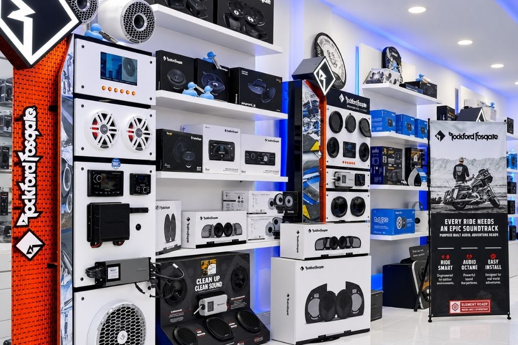 Rockford Fosgate car audio display featuring speakers, subwoofers, amplifiers, and audio accessories in a showroom.