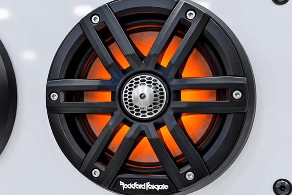 Close-up of a Rockford Fosgate car speaker with orange lighting.